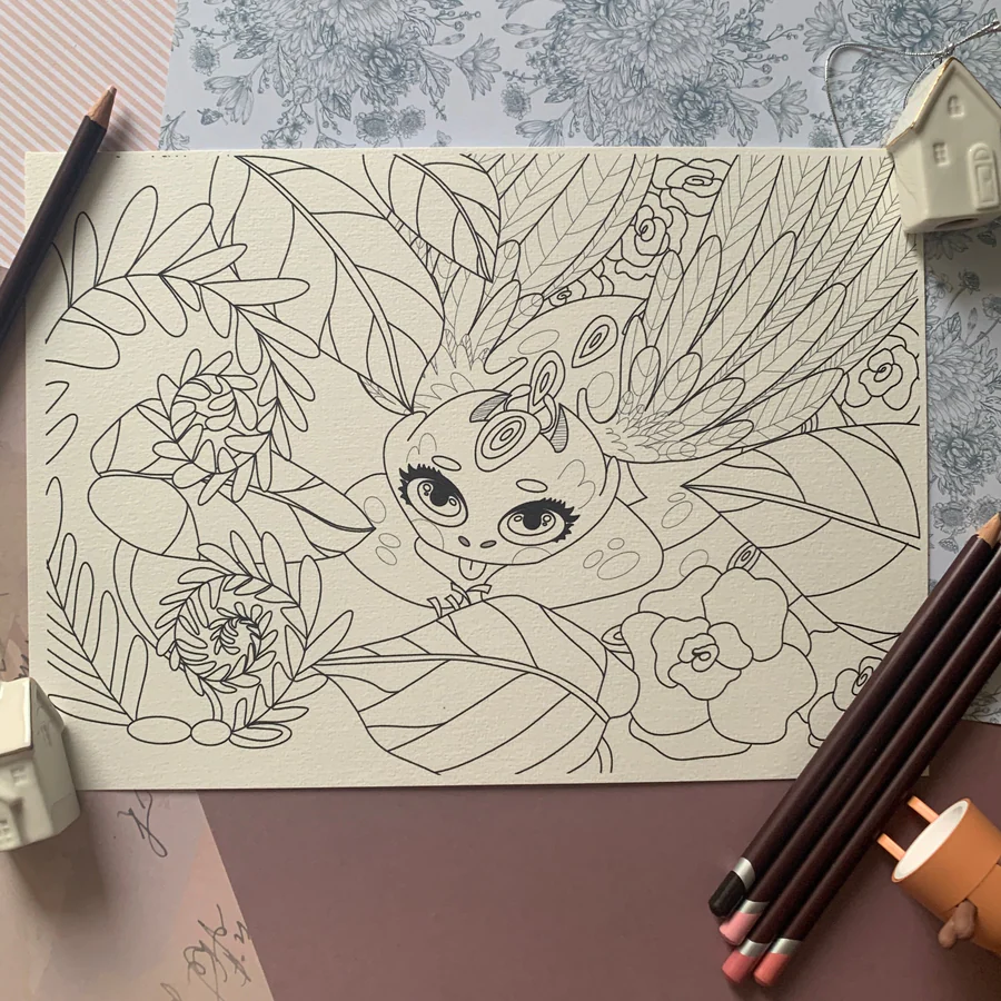 Petit dragon dessiné sur papier, entouré de crayons